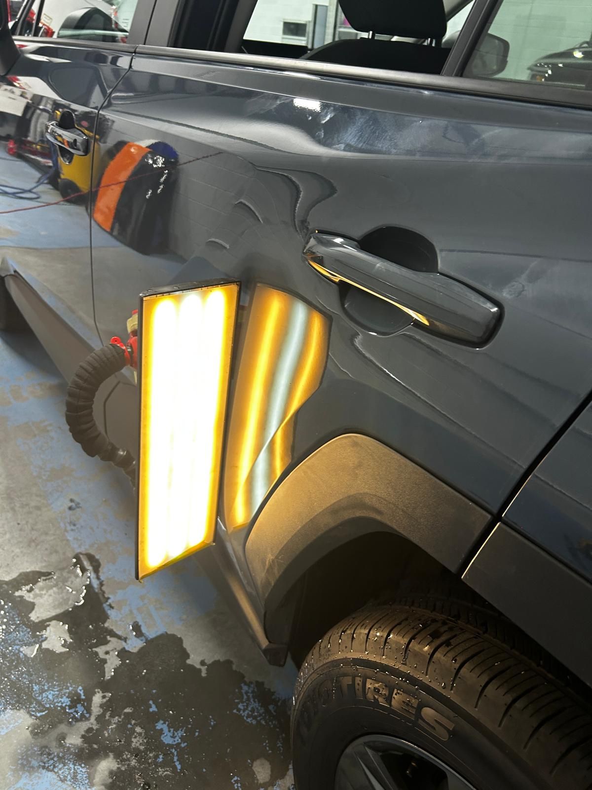 PDR reflection light board aimed at a creased quarter panel on a dark blue SUV