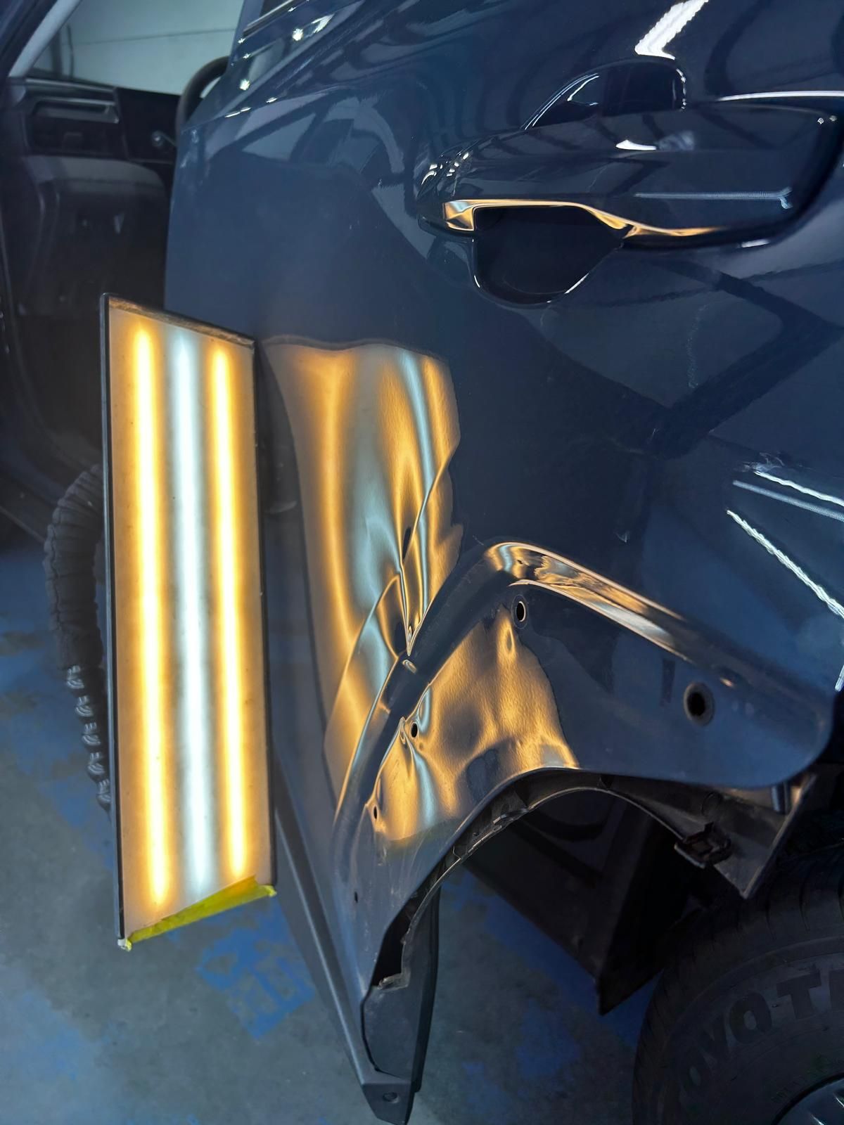 Wheel arch area of a dark blue SUV under PDR lighting with the liner removed