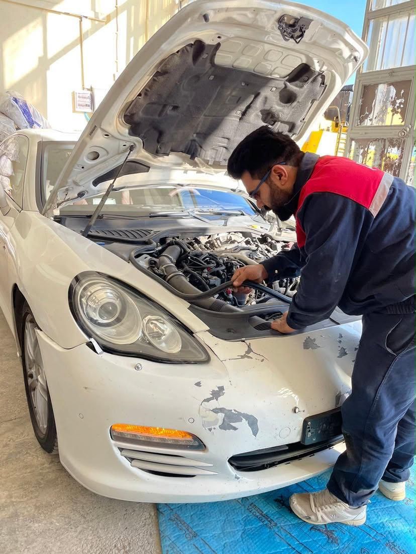 Sayed Sadat working under the hood of a white sedan with front-end damage