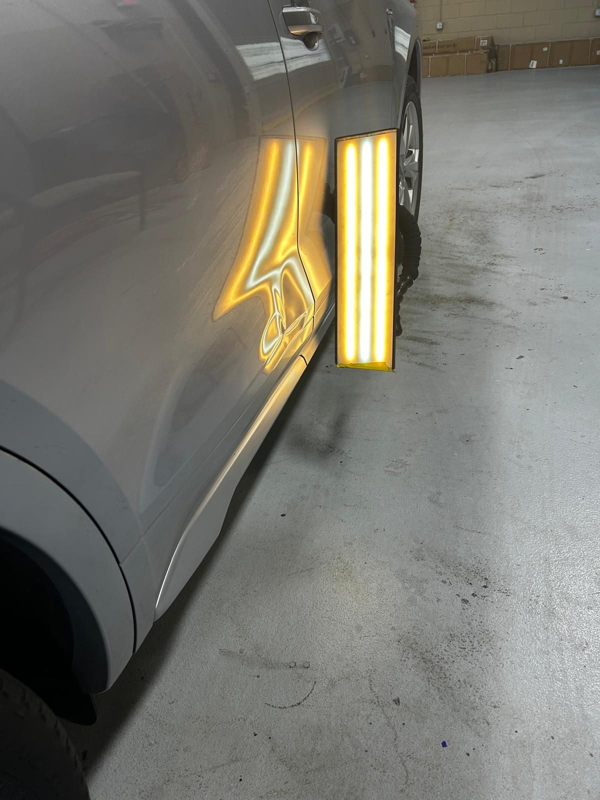 Reflection lines revealing a dent on a silver rear door